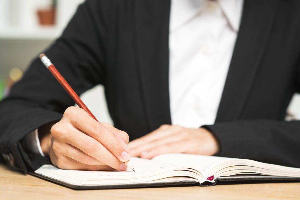 close up young businesswoman writing with red pencil diary